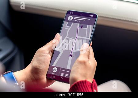 Online-Taxibuchung. Frau im Auto, die online ein Taxi über die mobile App auf ihrem Smartphone bestellt. Stockfoto