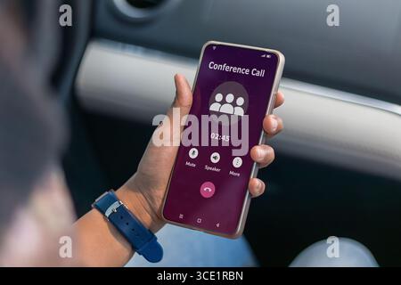 Eine muslimische Frau, die eine Telefonkonferenz macht, während sie mit dem Auto reist Stockfoto
