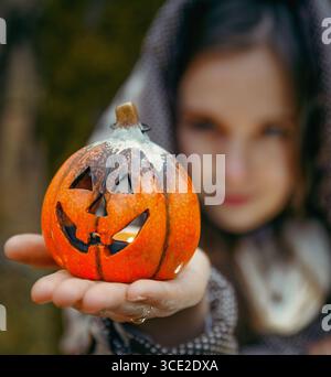 Eine Frau mit Kapuze hält eine Jack-o'-Laterne in den Händen Stockfoto
