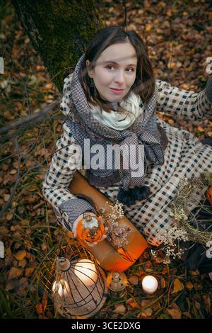 Frau im Kapuzenkostüm mit halloween Dekor im dunklen Wald Stockfoto