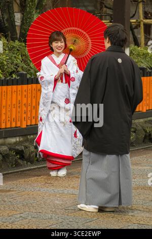 Junge japanische Frau mit traditionellen Kimono holding Regenschirm suchen bei der man auch die traditionellen Kimono gekleidet, Gion Shirakawa, Motoyoshicho, Higashi Stockfoto