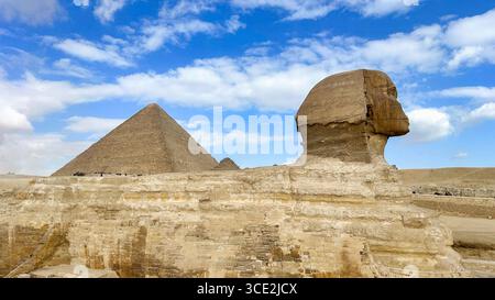 Die große Sphinx von Gizeh mit der berühmten Großen Pyramide im Hintergrund, ein zeitloser Blick auf die altägyptische Pracht. Stockfoto