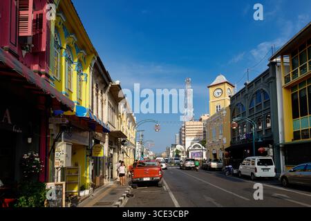 Farbenfrohe Geschäfte im chinesisch-portugiesischen Stil in der Phang-Nga Rd In der Altstadt von Phuket Town, Thailand, mit dem berühmten Phromthep Clocktower in b/g Stockfoto