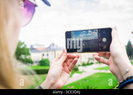 Eine Nahaufnahme, horizontale Aufnahme hinter einer Frau, die ein Smartphone hält, um ein Foto des historischen Schlosses Sondershausen aufzunehmen. Stockfoto