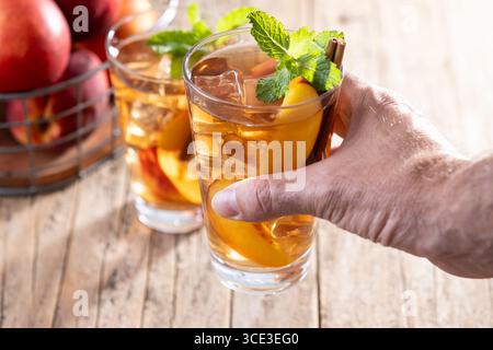 Erfrischender Pfirsicheistee im Glas mit Eiswürfeln auf Holztisch Stockfoto