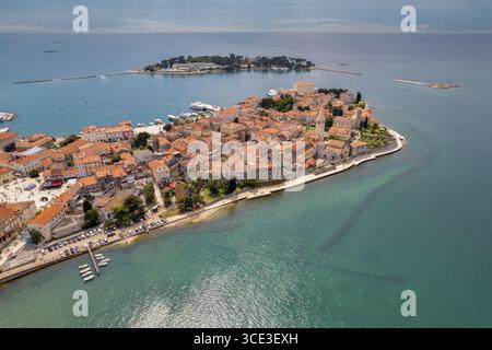 Drohnenblick auf die Altstadt von Porec und die Euphrasische Basilika an der istrischen Küste Kroatiens. Die rot gekachelten Dächer und historischen Gebäude ruhen auf Stockfoto