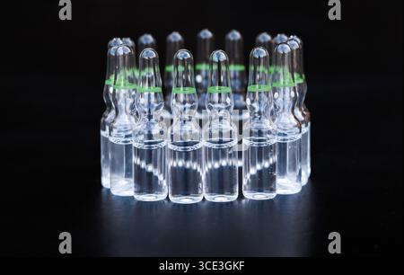 Kleine Glasampullen mit Arzneimitteln auf schwarzem Hintergrund. Stockfoto