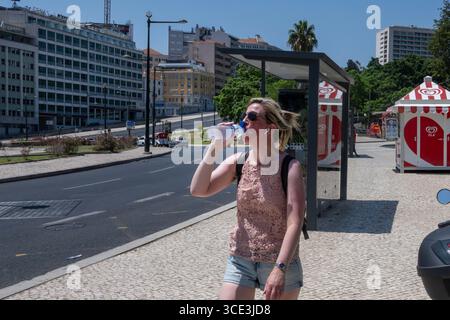 Lissabon, Portugal. August 2025. Eine Frau trinkt Wasser aus ihrer Flasche, während sie in der Nähe der Gärten des Parks Eduardo VII in Lissabon spaziert. In diesem Sommer hat Portugal es mit wirklich hohen Temperaturen zu tun, mit Thermometern, die weit über dem Normalwert liegen und städtische und ländliche Gebiete sowie Touristen auf die Probe stellen, und die Behörden warnen vor Bränden und Überhitzungsgefahr. Quelle: SOPA Images Limited/Alamy Live News Stockfoto