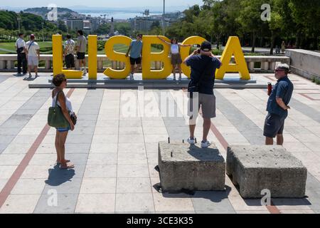 Lissabon, Portugal. August 2025. Man fotografiert an einem Schild mit dem Wort Lissabon, das sich in den Gärten des Parks Eduardo VII befindet. In diesem Sommer hat Portugal es mit wirklich hohen Temperaturen zu tun, mit Thermometern, die weit über dem Normalwert liegen und städtische und ländliche Gebiete sowie Touristen auf die Probe stellen, und die Behörden warnen vor Bränden und Überhitzungsgefahr. (Foto: Jorge Castellanos/SOPA Images/SIPA USA) Credit: SIPA USA/Alamy Live News Stockfoto