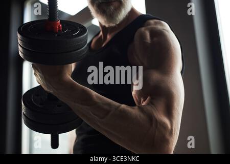 Kaukasischer Mann demonstriert Krafttraining mit schwerer Hantel drinnen Stockfoto