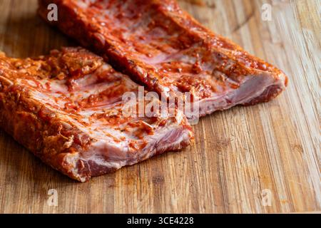 Rohe, gewürzte und marinierende Schweinerippchen oder Spare Rippchen auf einem hölzernen Küchenbrett. Nahaufnahme, keine Leute Stockfoto