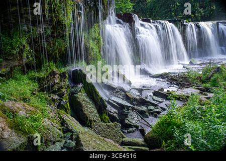 Malerischer Wasserfall, der über moosige Felsen in üppiger grüner Umgebung stürzt. Keila-Joa Stockfoto