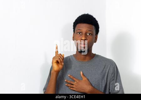 Junger Teenager in grauem T-Shirt, posiert vor weißem Hintergrund. Konzept: Reflexion, Entscheidungsfindung, Planung, mentale Fokussierung, Fortschritt Stockfoto
