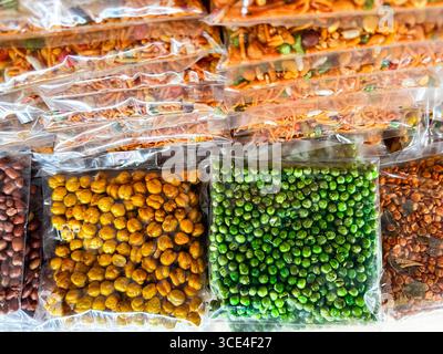 Verschiedene verpackte indische Snacks wie geröstete Kichererbsen und grüne Erbsen werden in transparenten Taschen an einem Marktstand in malaysia ausgestellt Stockfoto