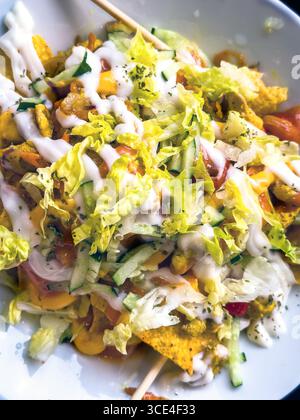 Detaillierte Nahaufnahme des farbenfrohen vegetarischen Taco-Salats mit Nachos, frischem Salat, Tomaten, Gurken und cremigem Dressing in einer weißen Schüssel. Malaysia Stockfoto