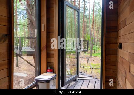 Einzigartig gestaltetes Holzbaumhaus mit einladendem Brückeneingang, umgeben von üppigem Wald. Perfekt für Naturrezepte, Öko-Frien Stockfoto