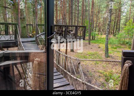 Einzigartig gestaltetes Holzbaumhaus mit einladendem Brückeneingang, umgeben von üppigem Wald. Perfekt für Naturrezepte, Öko-Frien Stockfoto