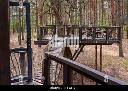 Einzigartig gestaltetes Holzbaumhaus mit einladendem Brückeneingang, umgeben von üppigem Wald. Perfekt für Naturrezepte, Öko-Frien Stockfoto