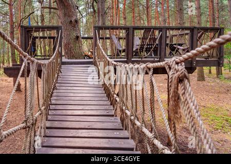 Einzigartig gestaltetes Holzbaumhaus mit einladendem Brückeneingang, umgeben von üppigem Wald. Perfekt für Naturrezepte, Öko-Frien Stockfoto