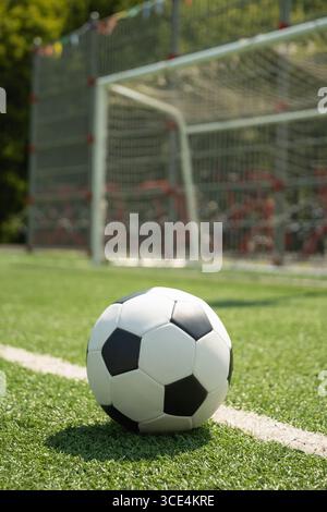 Fußball auf dem grünen Rasenfeld vor dem Fußballtor. Fußball auf dem Feld vor dem Torpfosten. Konzentriere dich auf den Ball. Hintergrund des Fußballstadions. Im Freien Stockfoto