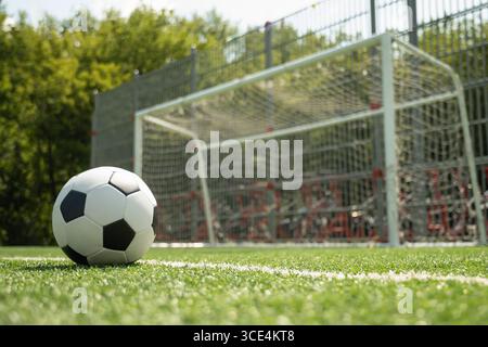 Fußball auf dem grünen Rasenfeld vor dem Fußballtor. Fußball auf dem Feld vor dem Torpfosten. Konzentriere dich auf den Ball. Hintergrund des Fußballstadions. Sommer Stockfoto