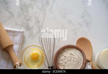 Zutaten und Werkzeuge sind ordentlich angeordnet, einschließlich Mehl, ein Ei und Backutensilien, was die Zubereitung eines Rezepts in der Küche andeutet. Stockfoto