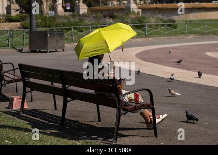 Ein asiatischer Tourist auf der Plaza de Catalunya, der sich mit einem Sonnenschirm vor der Sonne und hohen Temperaturen schützt. Die Küste von Barcelona ist unter extremer Wetterwarnung mit hohen Temperaturen. Die Stadt leidet seit Wochen unter hohen Temperaturen. Die Hitze beeinträchtigt die Gesundheit der Bewohner, belästigt den Tourismus und erschöpft Obdachlose. Stockfoto