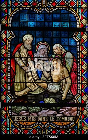 Rochefort, Belgien - 23. Juli 2025: Buntglasfenster, in dem Jesus nach der Kreuzigung in das Grab gelegt wird, mit Maria und anderen Jüngern Stockfoto