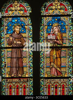 Rochefort, Belgien - 23. Juli 2025: Buntglasfenster, das den Heiligen Franziskus mit einem Kruzifix und die Heilige Clotilde mit einem Kirchenmodell zeigt Stockfoto