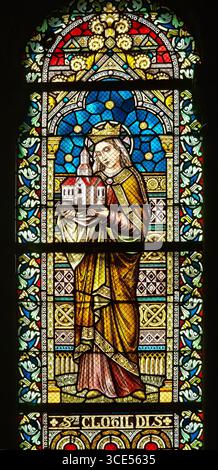 Rochefort, Belgien - 23. Juli 2025: Buntglasfenster mit der gekrönten und mit einem Kirchenmodell versehenen Heiligen Clotilde in der Kirche Rochefort, Belgien. Stockfoto