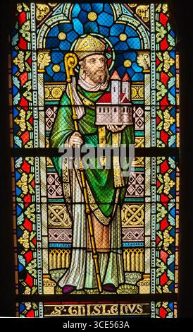 Rochefort, Belgien - 23. Juli 2025: Buntglasfenster mit dem Heiligen Ghislain, frühchristlicher Abt und Kirchengründer, der ein Modell einer Kirche hält Stockfoto