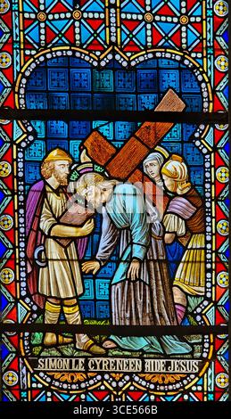 Rochefort, Belgien - 23. Juli 2025: Buntglasfenster mit der fünften Station des Kreuzes: Simon von Kyrene hilft Jesus, sein Kreuz zu tragen Stockfoto