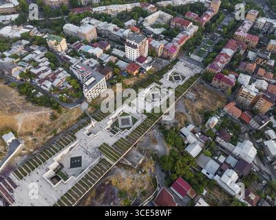 Aus der Vogelperspektive auf kaskadierende Springbrunnen und gepflegte Rasenflächen des Yerevan Kaskadenzkomplexes, eingerahmt von der Architektur der Stadt Jerewan, Jerewan, Armenien. Stockfoto
