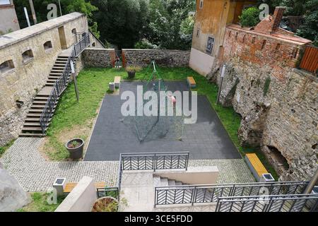 Historischer Spielplatz im Innenhof mit Kletternetz und Steinmauern in Kłodzko, Polen Stockfoto