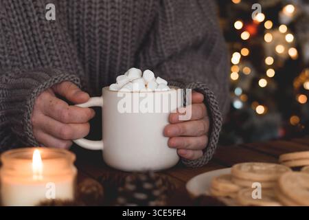 Frauenhände in kuscheliger Pullover mit Tasse mit heißer Schokolade und Marshmallows Stockfoto