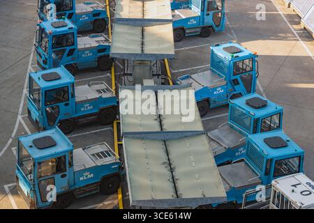 AMSTERDAM, NIEDERLANDE, 03. JULI 2025, am Flughafenterminal geparkte Fahrzeuge mit blauem Boden, die für Transportwagen verwendet werden Stockfoto