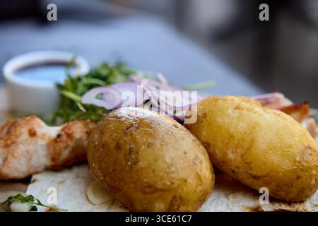 Gericht mit gekochten Kartoffeln mit gegrillten Hähnchenspießen und Sauce Stockfoto