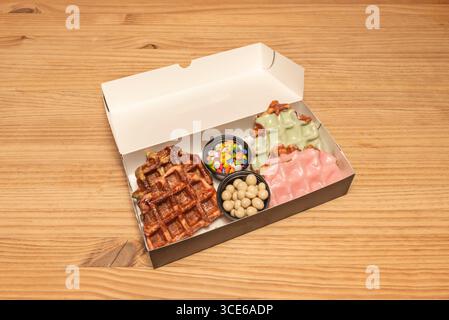 Tropische Waffeln: Mango, Kiwi und frische Ananaswürfel auf Kokoscreme und Limettenschale Stockfoto