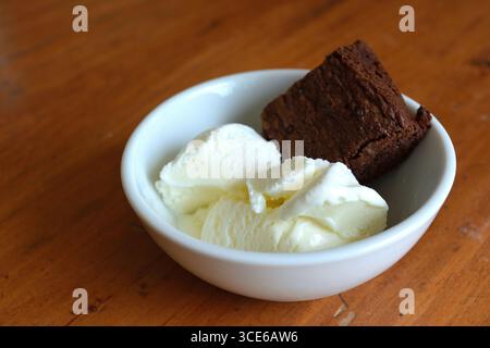 Ein Nachtisch aus einem reichhaltigen Schokoladenbrownie mit zwei Kugeln Vanilleeis in einer weißen Schüssel 3 Stockfoto