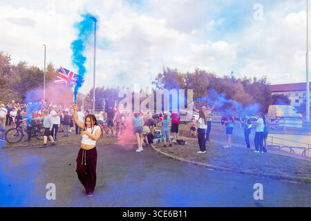Leeds, Großbritannien. AUGUST 2025. Junge Person hält bunte Fackeln, als sich in der vierten Woche die gegnerischen Pro- und Anti-Migrant-Demonstranten am Straßenrand in der Nähe des Britannia Hotels in Seacroft, Leeds, versammelten. Die Demonstranten der 'Stand Up Leeds' zündeten mehrere Fackeln an, und drei Gegenprotestierende wurden verhaftet, nachdem es zwischen Aktivisten und Polizei zu Streitigkeiten gekommen war. Credit Milo Chandler/Alamy Live News Stockfoto