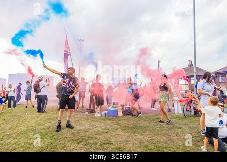 Leeds, Großbritannien. AUGUST 2025. Die Demonstranten setzten farbenfrohe Fackeln aus, als sich in der vierten Woche gegensätzliche Pro- und Anti-Migrant-Demonstranten am Straßenrand in der Nähe des Britannia Hotels in Seacroft, Leeds, versammelten. Die Demonstranten der 'Stand Up Leeds' zündeten mehrere Fackeln an, und drei Gegenprotestierende wurden verhaftet, nachdem es zwischen Aktivisten und Polizei zu Streitigkeiten gekommen war. Credit Milo Chandler/Alamy Live News Stockfoto