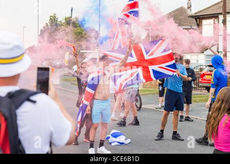 Leeds, Großbritannien. AUGUST 2025. Die Demonstranten setzten farbenfrohe Fackeln aus, als sich in der vierten Woche gegensätzliche Pro- und Anti-Migrant-Demonstranten am Straßenrand in der Nähe des Britannia Hotels in Seacroft, Leeds, versammelten. Die Demonstranten der 'Stand Up Leeds' zündeten mehrere Fackeln an, und drei Gegenprotestierende wurden verhaftet, nachdem es zwischen Aktivisten und Polizei zu Streitigkeiten gekommen war. Credit Milo Chandler/Alamy Live News Stockfoto