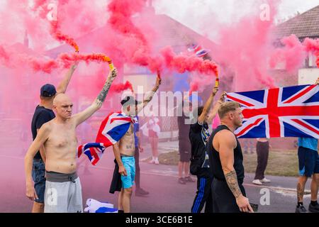 Leeds, Großbritannien. AUGUST 2025. Die Demonstranten setzten farbenfrohe Fackeln aus, als sich in der vierten Woche gegensätzliche Pro- und Anti-Migrant-Demonstranten am Straßenrand in der Nähe des Britannia Hotels in Seacroft, Leeds, versammelten. Die Demonstranten der 'Stand Up Leeds' zündeten mehrere Fackeln an, und drei Gegenprotestierende wurden verhaftet, nachdem es zwischen Aktivisten und Polizei zu Streitigkeiten gekommen war. Credit Milo Chandler/Alamy Live News Stockfoto