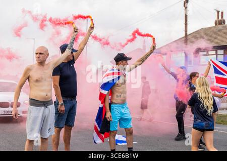 Leeds, Großbritannien. AUGUST 2025. Die Demonstranten setzten farbenfrohe Fackeln aus, als sich in der vierten Woche gegensätzliche Pro- und Anti-Migrant-Demonstranten am Straßenrand in der Nähe des Britannia Hotels in Seacroft, Leeds, versammelten. Die Demonstranten der 'Stand Up Leeds' zündeten mehrere Fackeln an, und drei Gegenprotestierende wurden verhaftet, nachdem es zwischen Aktivisten und Polizei zu Streitigkeiten gekommen war. Credit Milo Chandler/Alamy Live News Stockfoto