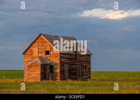 Dunkle Sturmwolken über einem alten, verlassenen Haus in den Prärien nördlich von Rush Lake, Saskatchewan Stockfoto