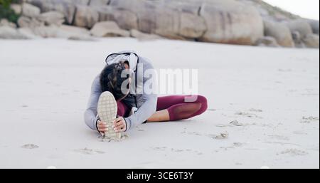 Fitness, Bewegung und Frau mit Stretching am Strand, um zu laufen, Cardio-Workout und Gesundheit. Athlet, Person und Beine wärmen sich am Meer für auf Stockfoto