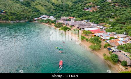 Aus der Vogelperspektive auf Santa Marta, Magdalena, mit farbenfrohen Häusern, Sandstrand und Booten auf klarem Wasser, umgeben von üppigen grünen Hügeln. Stockfoto