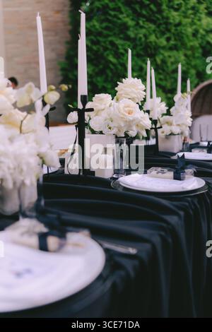 Eleganter festlicher Empfang im Freien in Schwarz-weiß mit Blumenmustern und hohen Kerzen im üppigen Grün für ein schickes und romantisches Konzert Stockfoto