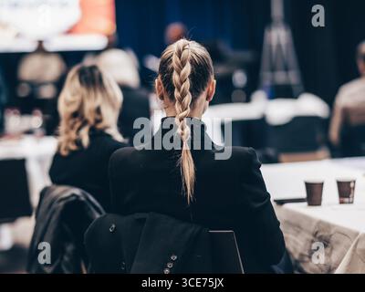 Rückansicht einer nicht erkennbaren Geschäftsfrau, die schöne Haarbrötchen trägt, die an einer Konferenz teilnimmt Stockfoto