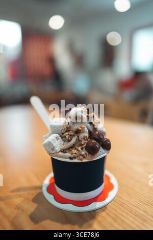 Gefrorener Joghurt in der Tasse mit Schokoladennüssen Marshmallows Belag, stilvolle Köstlichkeiten und süße Verwöhnung, cremiges, weiches Dessert mit Gourmet Stockfoto